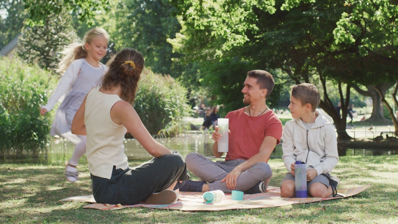 Familie auf einer Picknickdecke im Park, mehrere UNDA Flaschen daneben